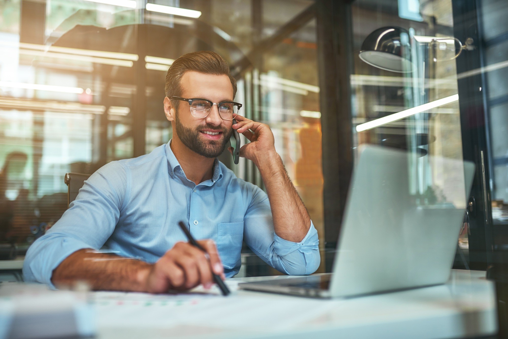 Customer support. Portrait of young and cheerful businessman in eyeglasses and formal wear talking